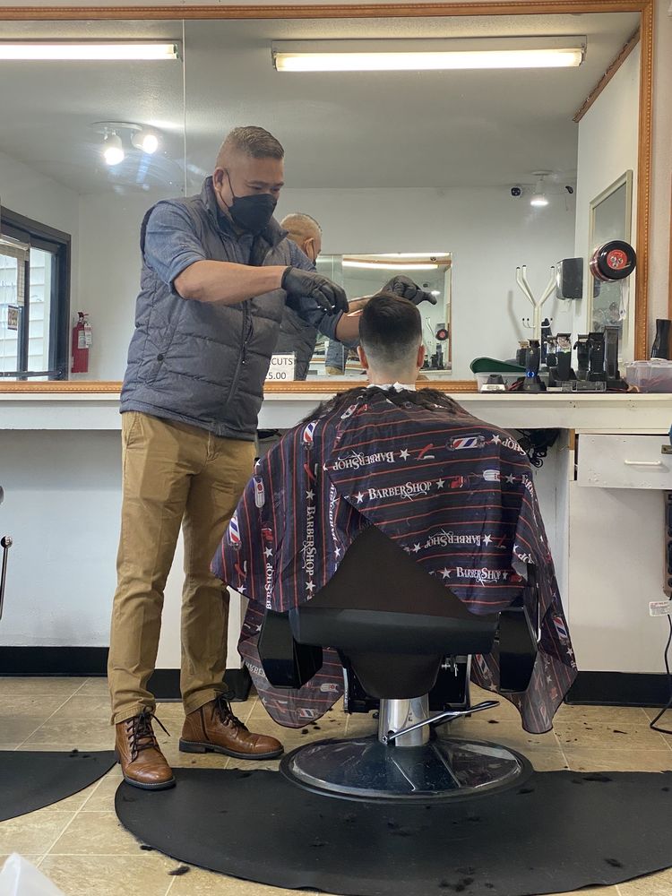 Barber giving a customer a haircut at Jess Barber Shop