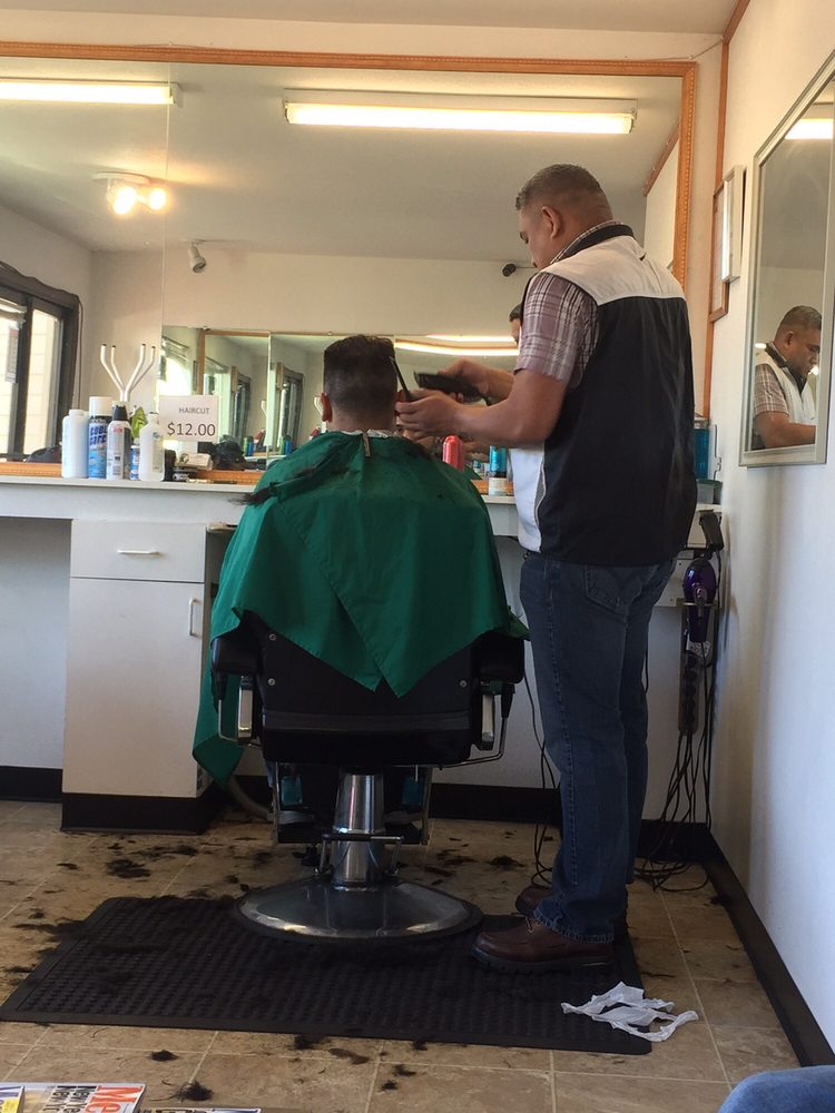 Barber station mirror with clippers, grooming tools and a haircut price sign at Jess Barber Shop
